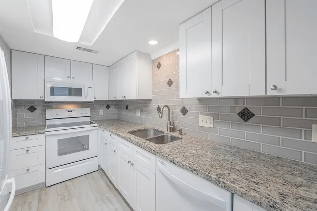 a kitchen with granite countertop white cabinets and white appliances