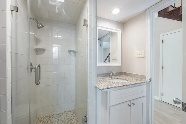 a bathroom with a granite countertop sink a mirror and a shower