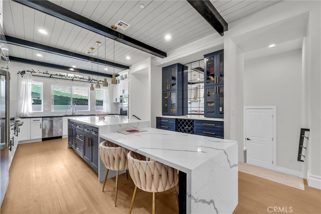 451 Avenida Esplendor Walnut, CA 91789 - Photo 14 of 51 a kitchen with stainless steel appliances kitchen island granite countertop a table chairs in it and wooden floors