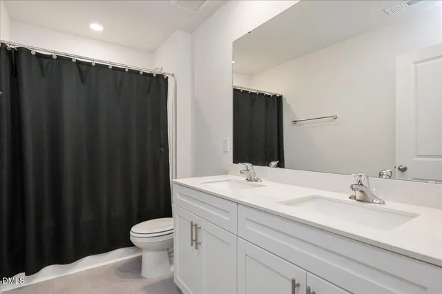 a bathroom with a sink a toilet a mirror and shower curtain