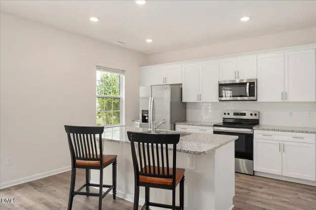 a kitchen with stainless steel appliances granite countertop a stove a sink a microwave a dining table and chairs