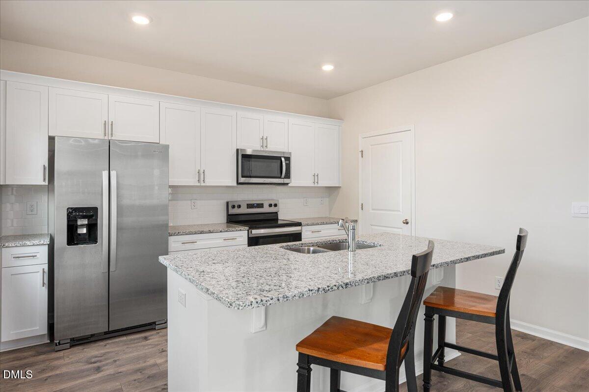 10 Whispering Willow Circle Youngsville, NC 27596 - Photo 7 of 28 a kitchen with stainless steel appliances granite countertop a dining table chairs refrigerator and microwave