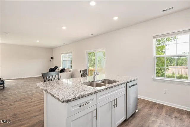 a kitchen with granite countertop a sink and dishwasher with wooden floor