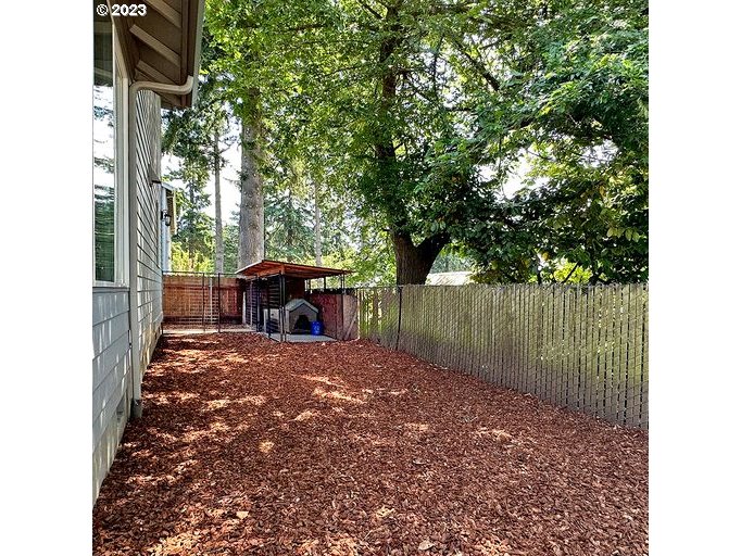 12614 Southeast Tibbetts Street Portland, OR 97236 - Photo 26 of 31 a view of a backyard with large trees and wooden fence