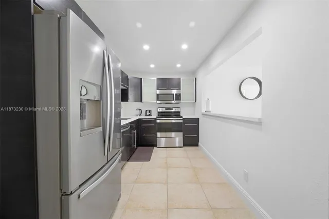 a large kitchen with stainless steel appliances granite countertop a refrigerator and a stove top oven