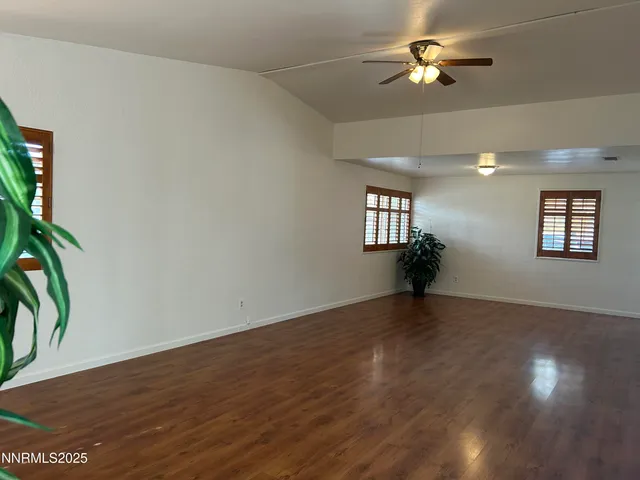 a view of an empty room with a window and wooden floor