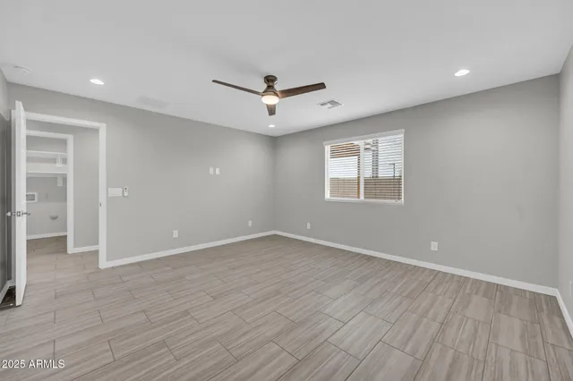 an empty room with wooden floor ceiling fan and windows