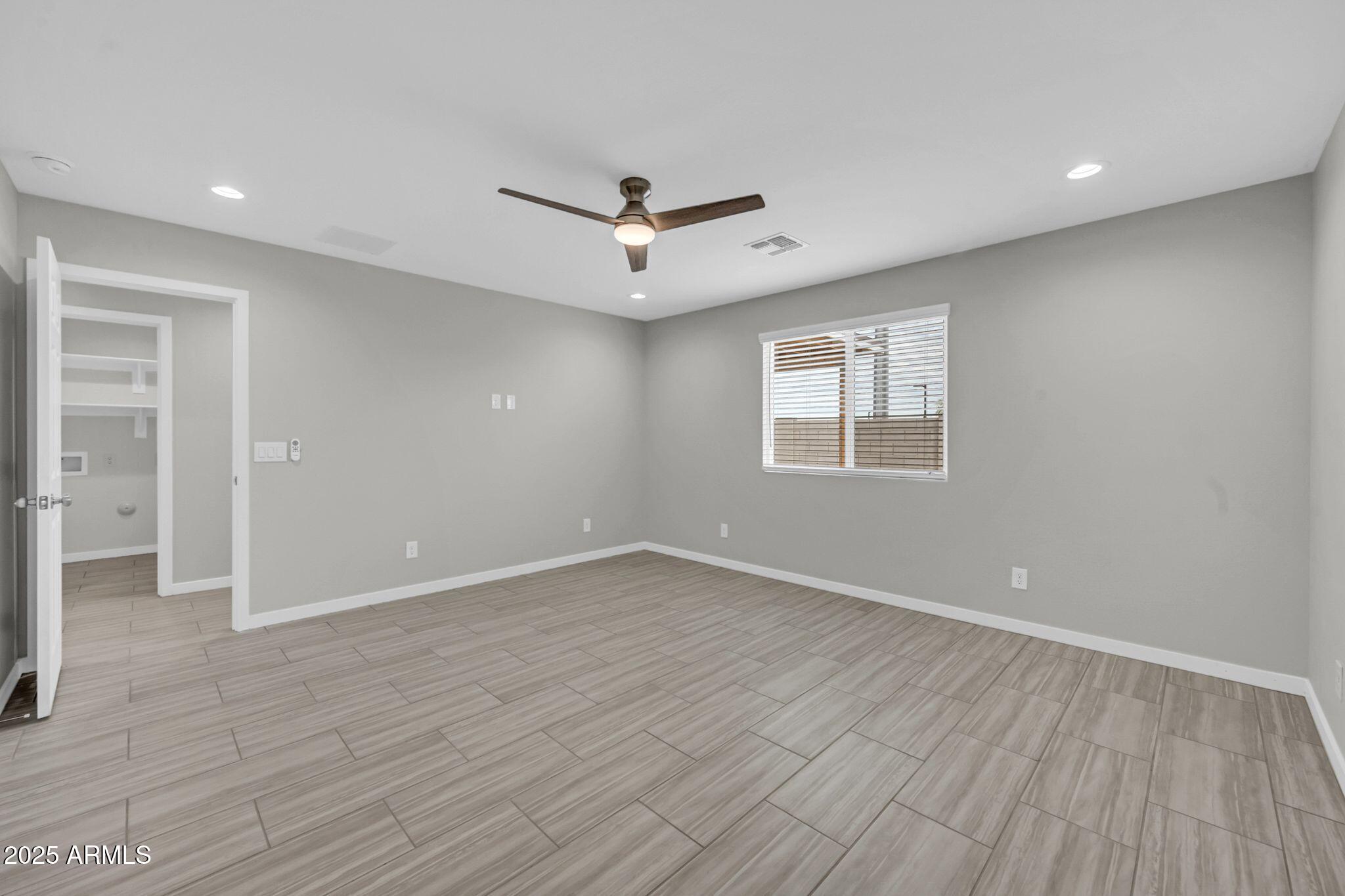 13215 South Laredo Road Arizona City, AZ 85123 - Photo 8 of 31 an empty room with wooden floor ceiling fan and windows