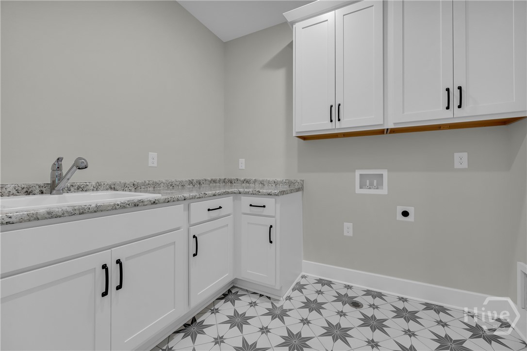 2476 St Martin Way Monroe, GA 30656 - Photo 52 of 75 Utility room featuring star-patterned floor tiling, white cabinetry with black hardware, a built-in sink with a pull-down faucet, and ample countertop space