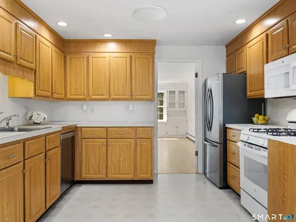 a kitchen with stainless steel appliances granite countertop a refrigerator a sink and white cabinets