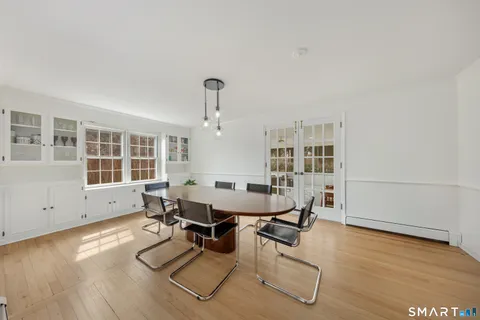 a dining room with wooden floor and a floor to ceiling window