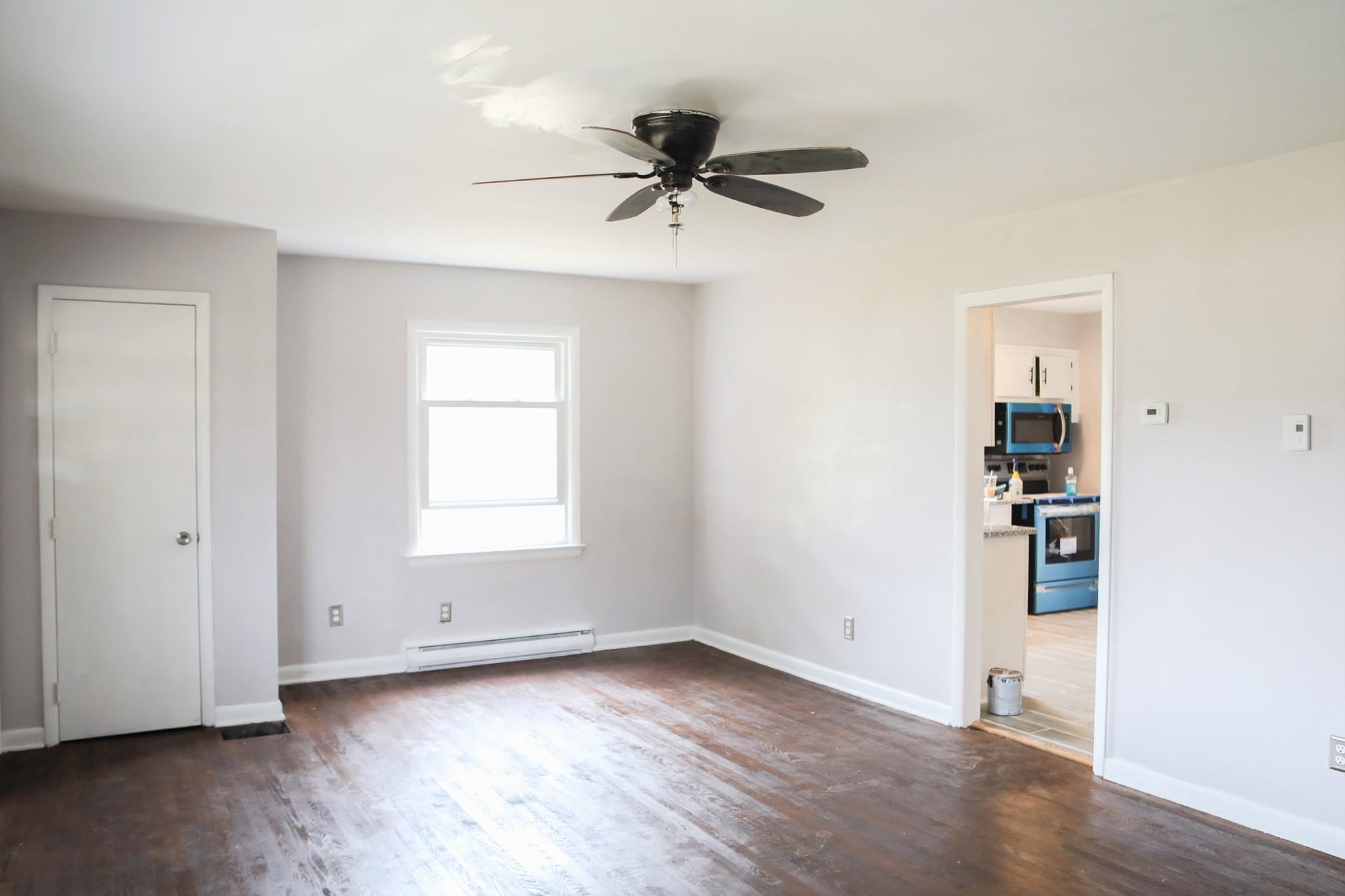 1613 Howardsville Road Staunton, VA 24401 - Photo 7 of 41 an empty room with wooden floor a ceiling fan and windows