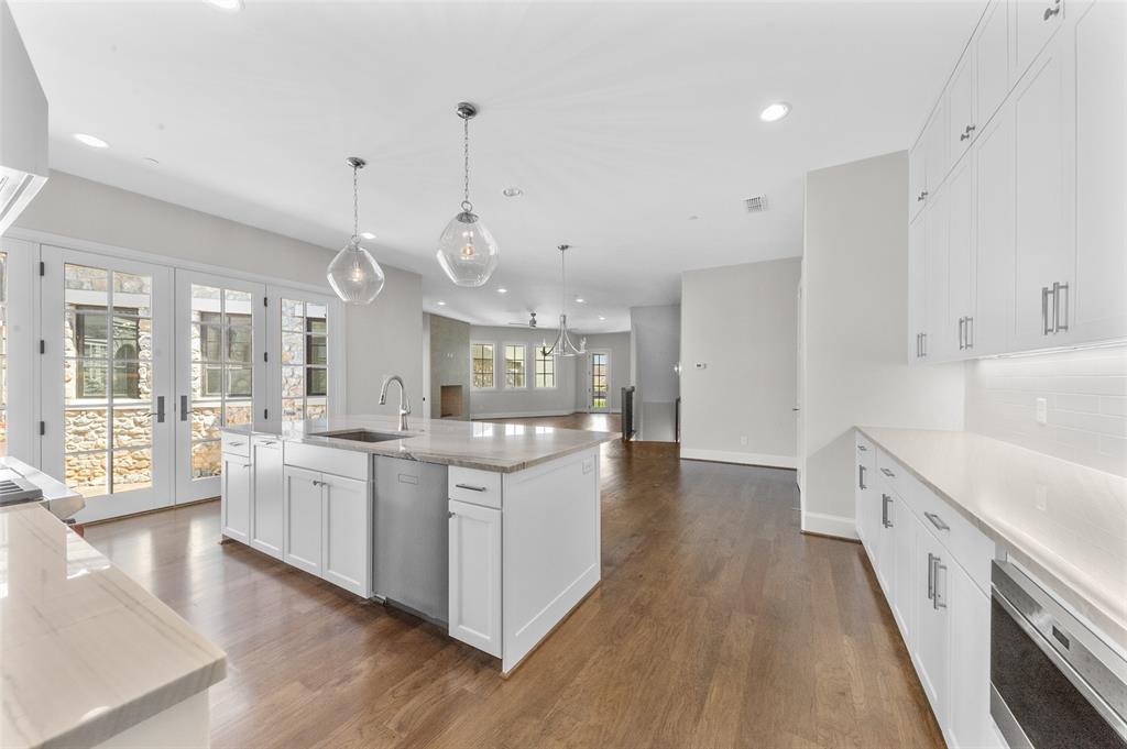 a large white kitchen with a large window a sink and stainless steel appliances