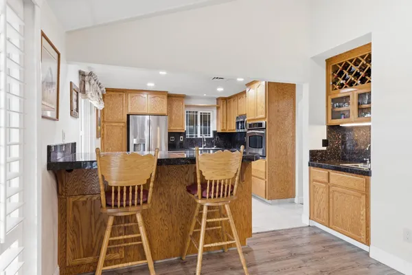 a view of kitchen with stainless steel appliances granite countertop dining table chairs cabinets and a sink