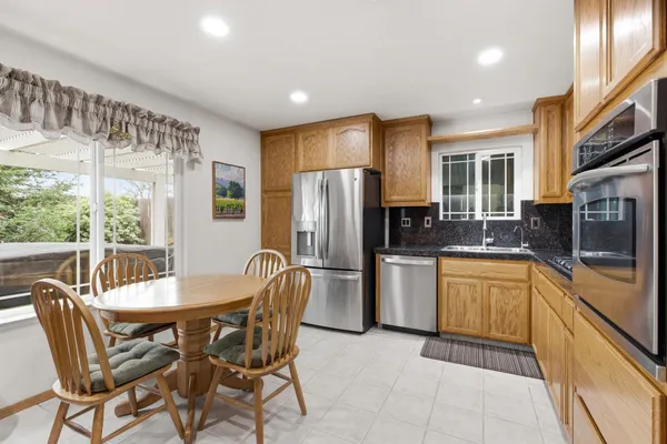 a kitchen with stainless steel appliances granite countertop a refrigerator a stove top oven a sink dishwasher and couches with wooden floor