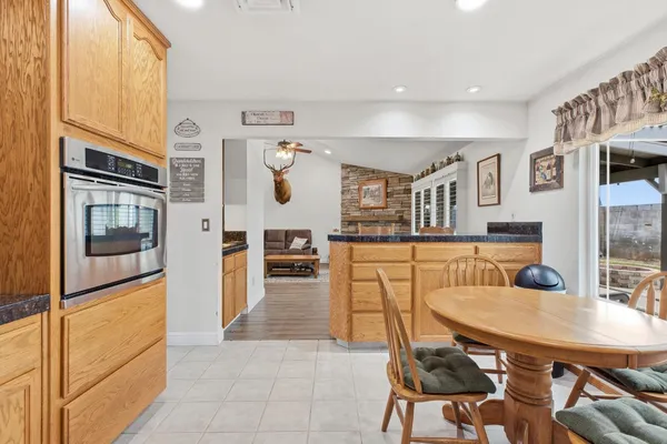 a kitchen with stainless steel appliances kitchen island granite countertop a refrigerator a stove and white cabinets with wooden floor