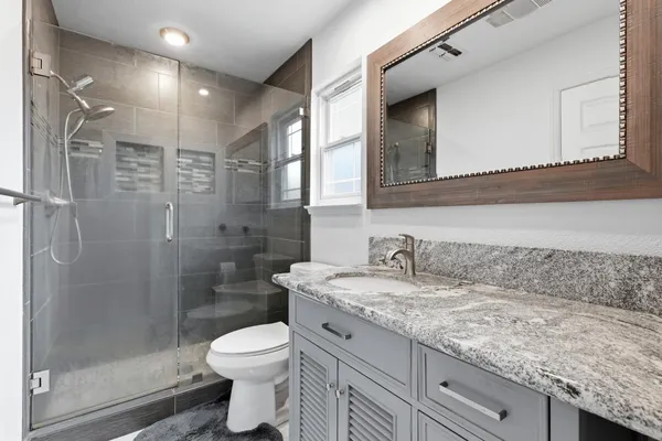 a bathroom with a granite countertop sink a toilet and shower