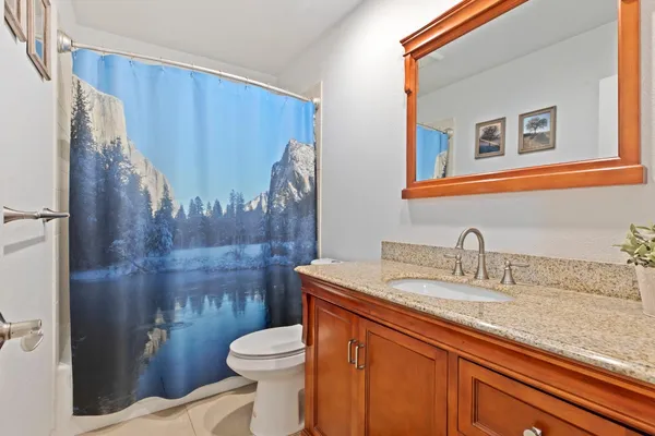 a bathroom with a granite countertop sink toilet and a mirror