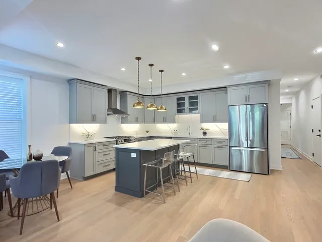 a kitchen with stainless steel appliances granite countertop a table chairs sink refrigerator and cabinets