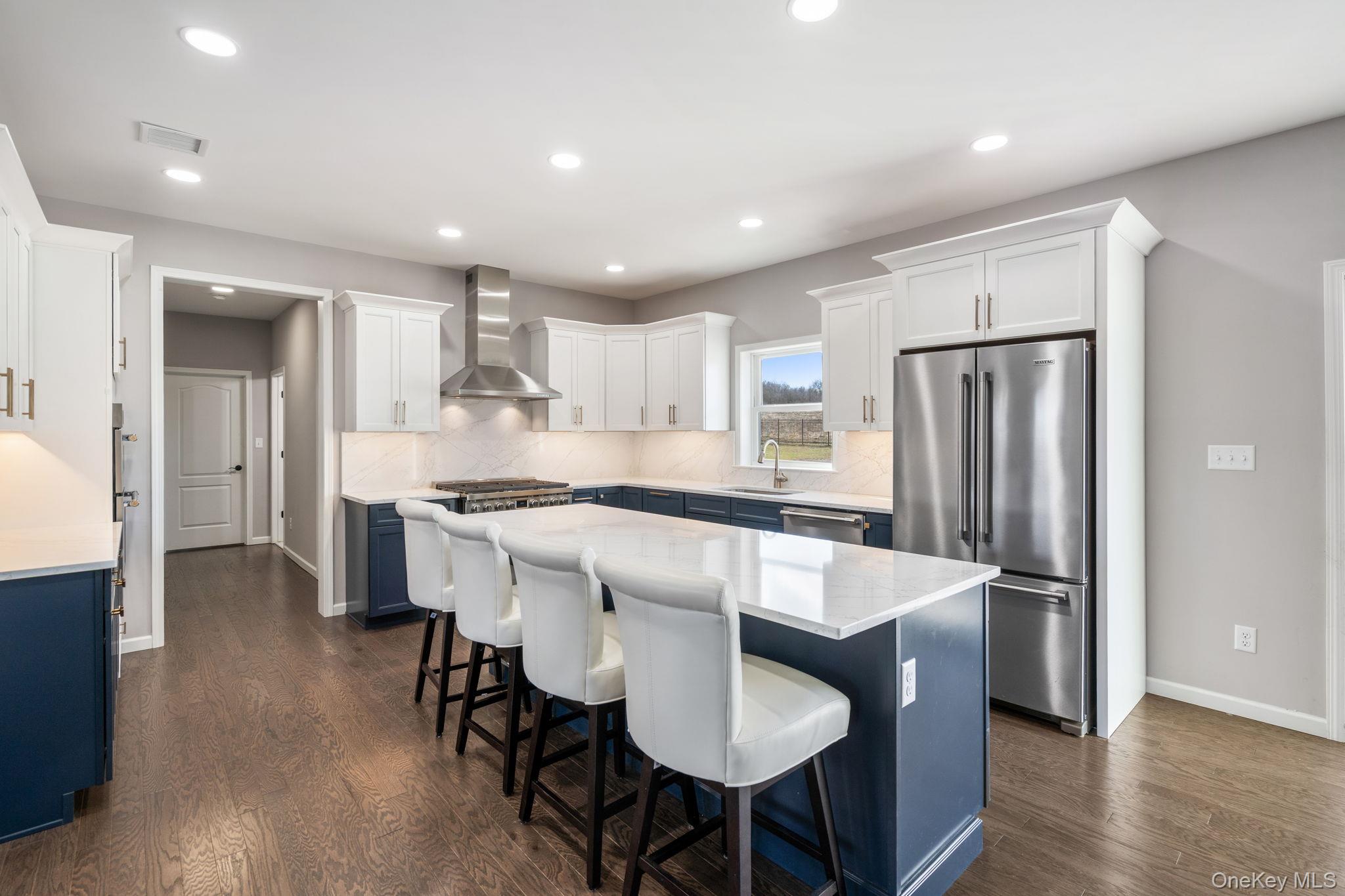 10 Harrier Ridge Drive Wallkill, NY 12589 - Photo 3 of 46 Kitchen featuring blue cabinetry, stainless steel appliances, white cabinets, a center island, and wall chimney exhaust hood
