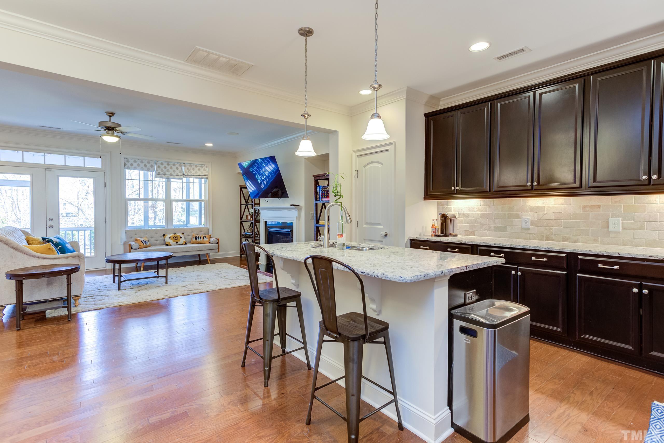 449 Talons Rest Way Cary, NC 27513 - Photo 14 of 54 a kitchen with stainless steel appliances granite countertop a stove top oven a refrigerator a sink and a dining table with wooden floor