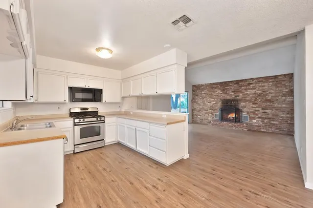 a white kitchen with wooden floor and stainless steel appliances