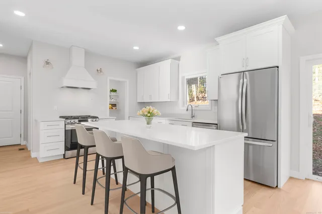 a kitchen with stainless steel appliances a refrigerator a sink a stove a dining table and chairs