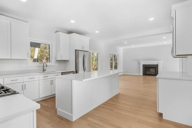a large white kitchen with cabinets a sink and a refrigerator