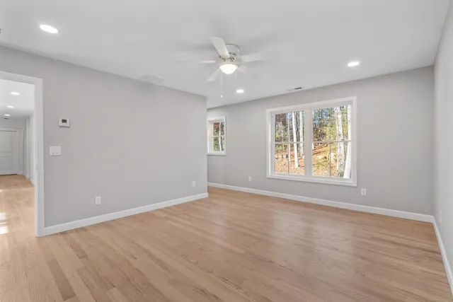 a view of an empty room with wooden floor and a window