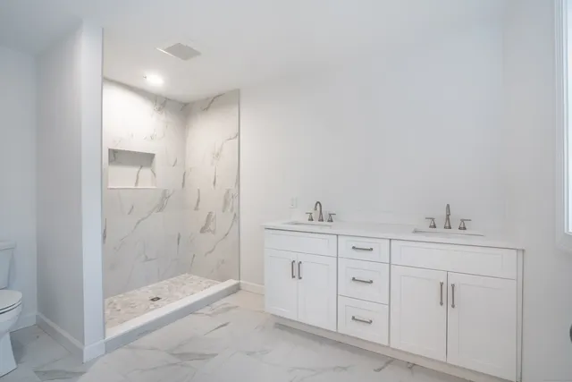 a spacious bathroom with a shower a mirror and a sink