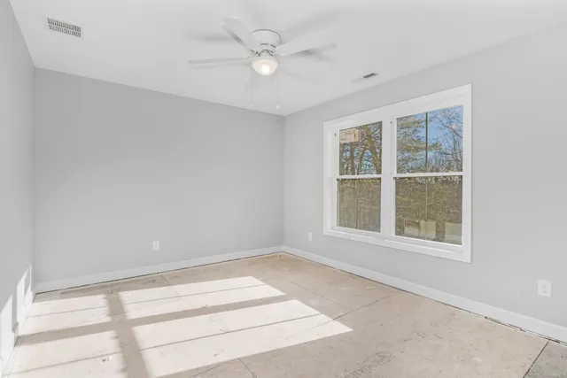 an empty room with windows and ceiling fan