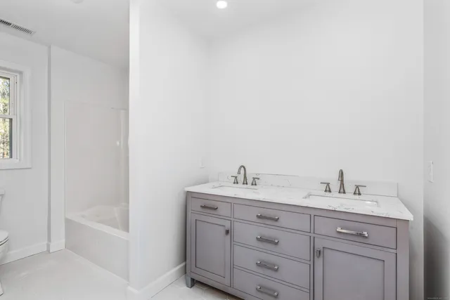 a bathroom with a granite countertop sink a toilet and bathtub