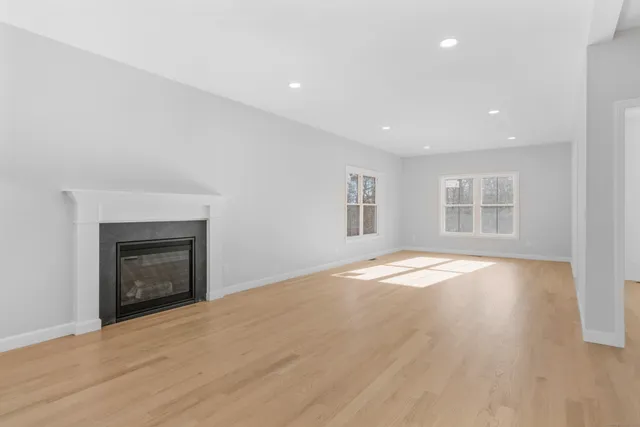 an empty room with wooden floor a fireplace and windows
