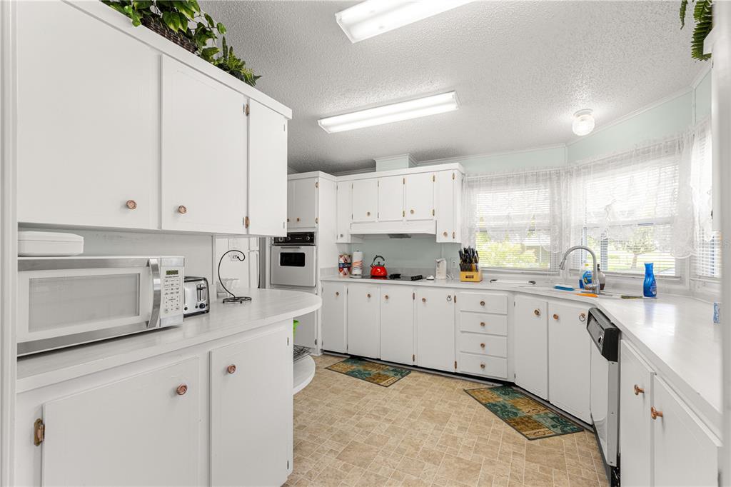 13081 Southeast 47th Court Belleview, FL 34420 - Photo 11 of 42 a kitchen with cabinets appliances a sink and a counter top space
