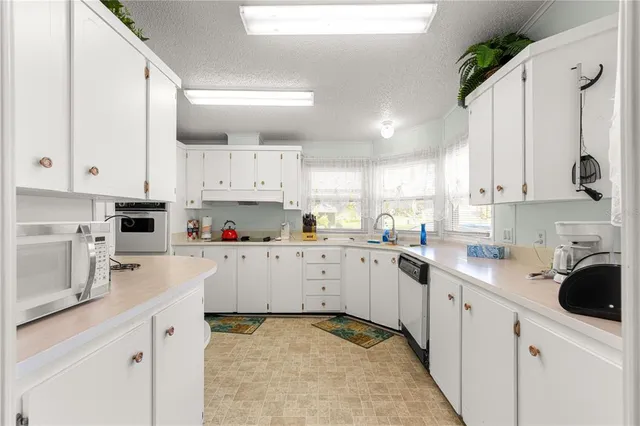 a kitchen with white cabinets sink and white appliances