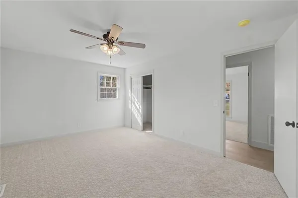an empty room with windows and fan chandelier