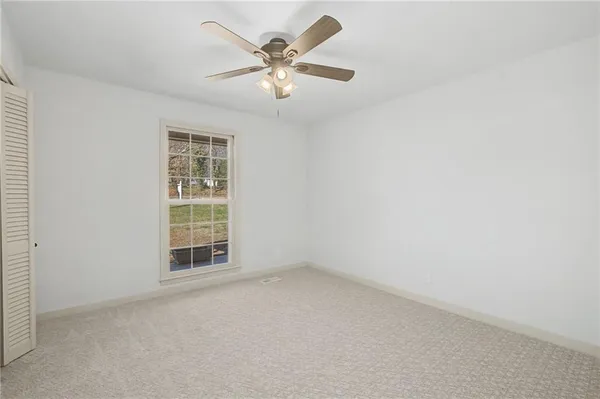 an empty room with windows and fan