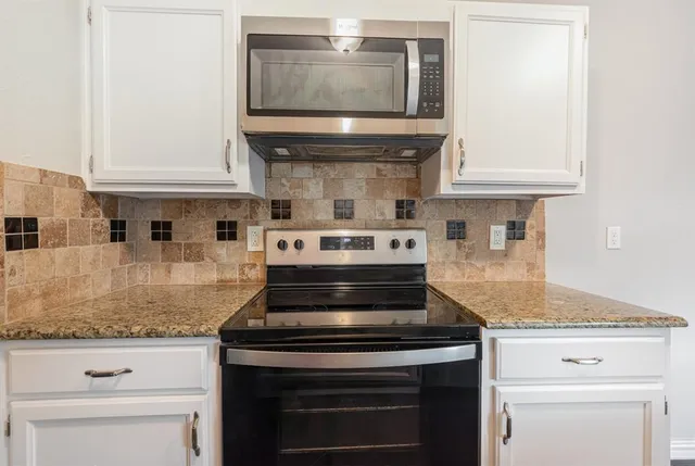 a stove top oven sitting inside of a kitchen and granite counter tops