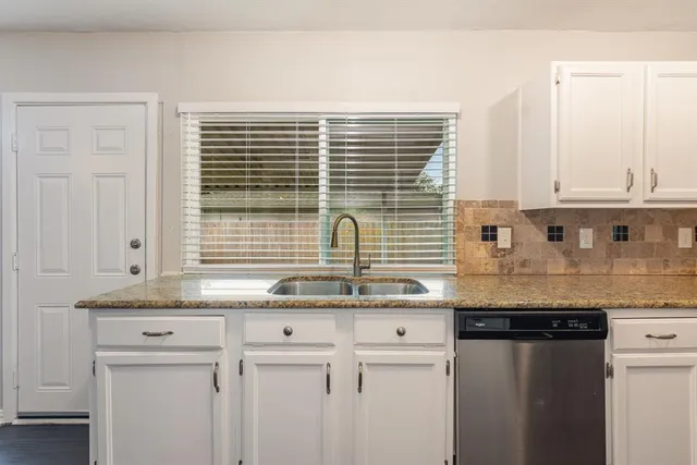 a kitchen with granite countertop white cabinets and a sink