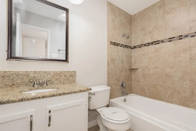 a bathroom with a granite countertop sink a toilet and shower