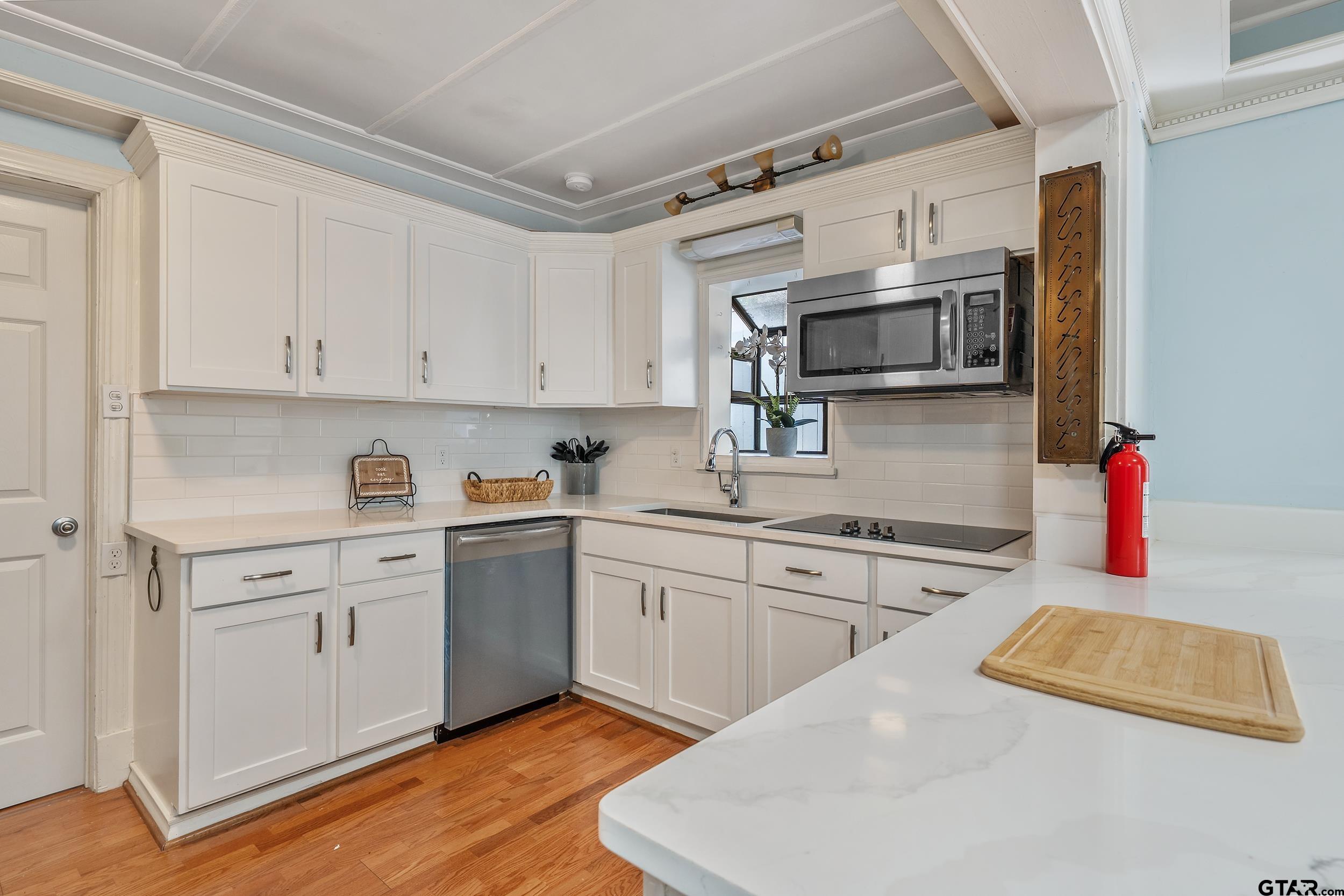 145 Rowland Place Tyler, TX 75701 - Photo 20 of 43 a kitchen with stainless steel appliances granite countertop a sink dishwasher and white cabinets with wooden floor
