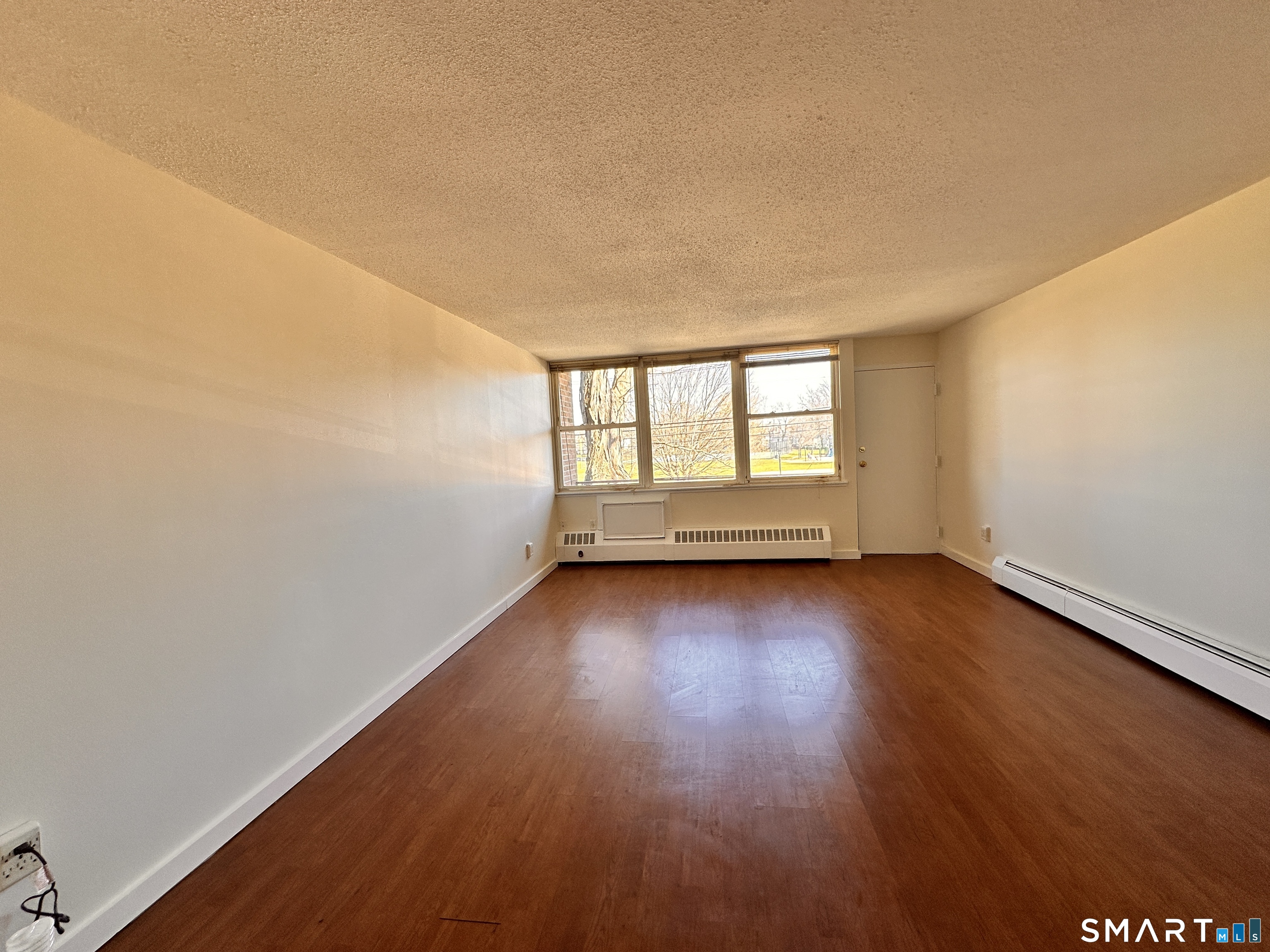 25 Ellsworth Street, Unit 17 Bridgeport, CT 06605 - Photo 11 of 30 an empty room with wooden floor and windows