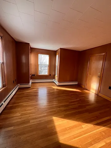 a view of an empty room with window and wooden floor