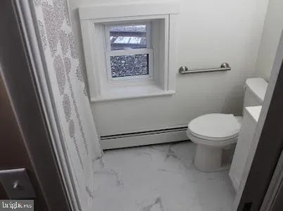a white toilet sitting next to a small window