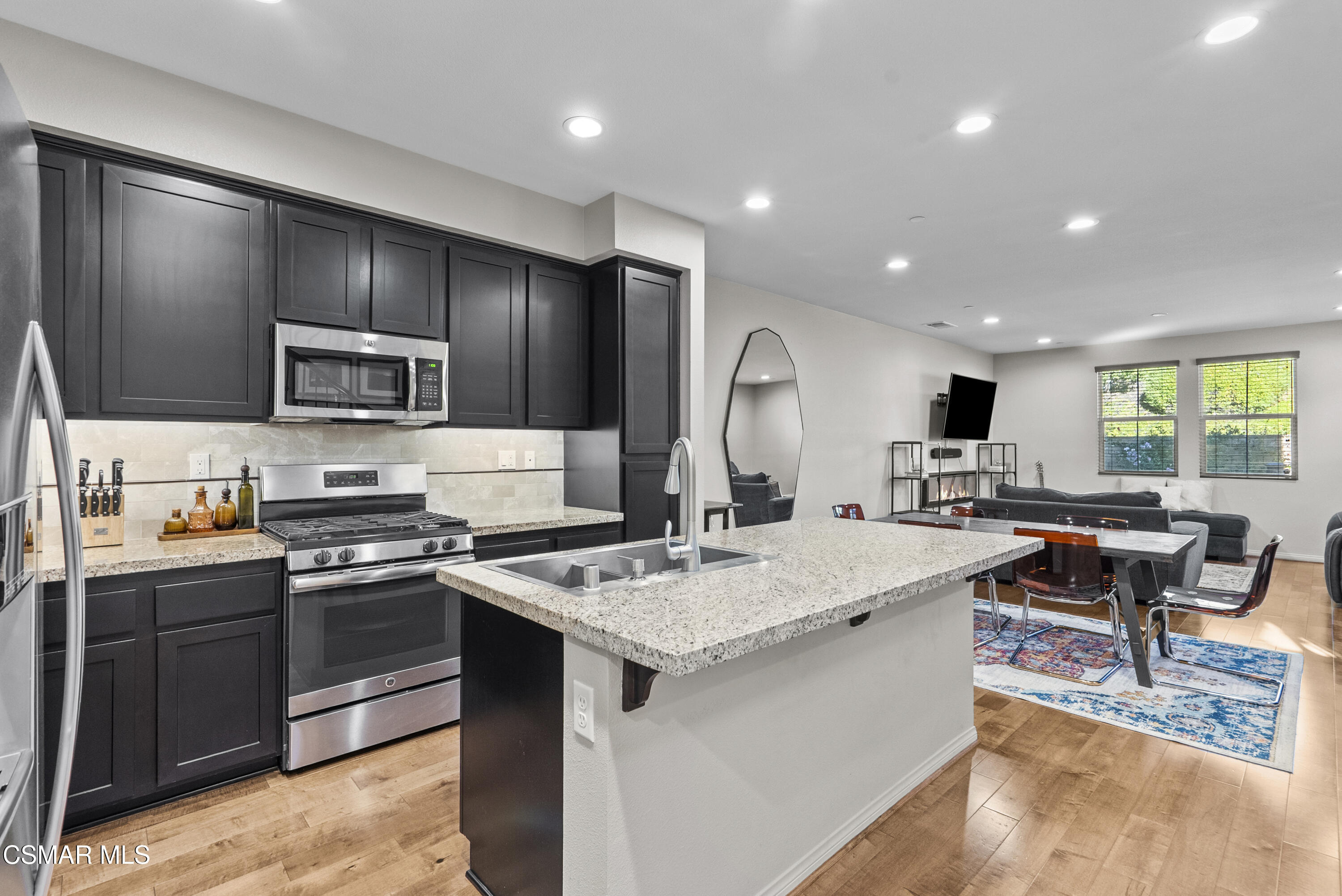 6441 Summit Village Lane, Unit 3 Simi Valley, CA 93063 - Photo 7 of 41 a large kitchen with stainless steel appliances a stove a sink a oven a dining table and chairs