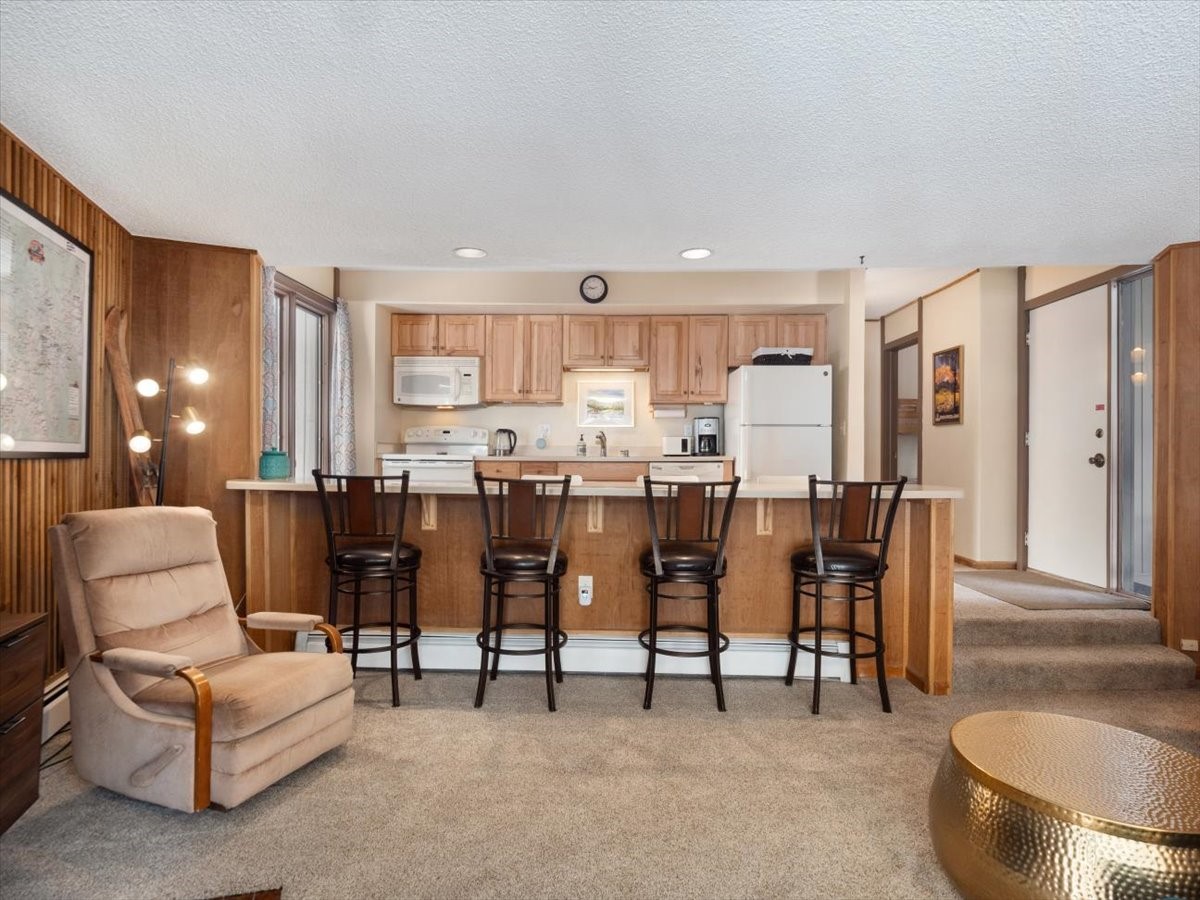 1161 Ski Hill Road, Unit 141 Breckenridge, CO 80424 - Photo 5 of 22 a living room with couches and kitchen view with wooden floor