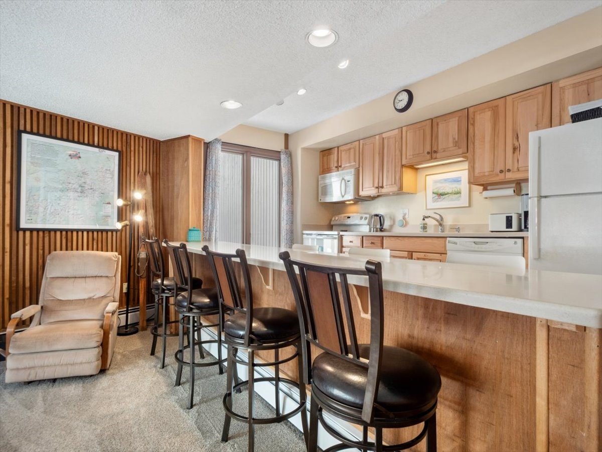 1161 Ski Hill Road, Unit 141 Breckenridge, CO 80424 - Photo 6 of 22 a kitchen with stainless steel appliances granite countertop a table chairs and a refrigerator