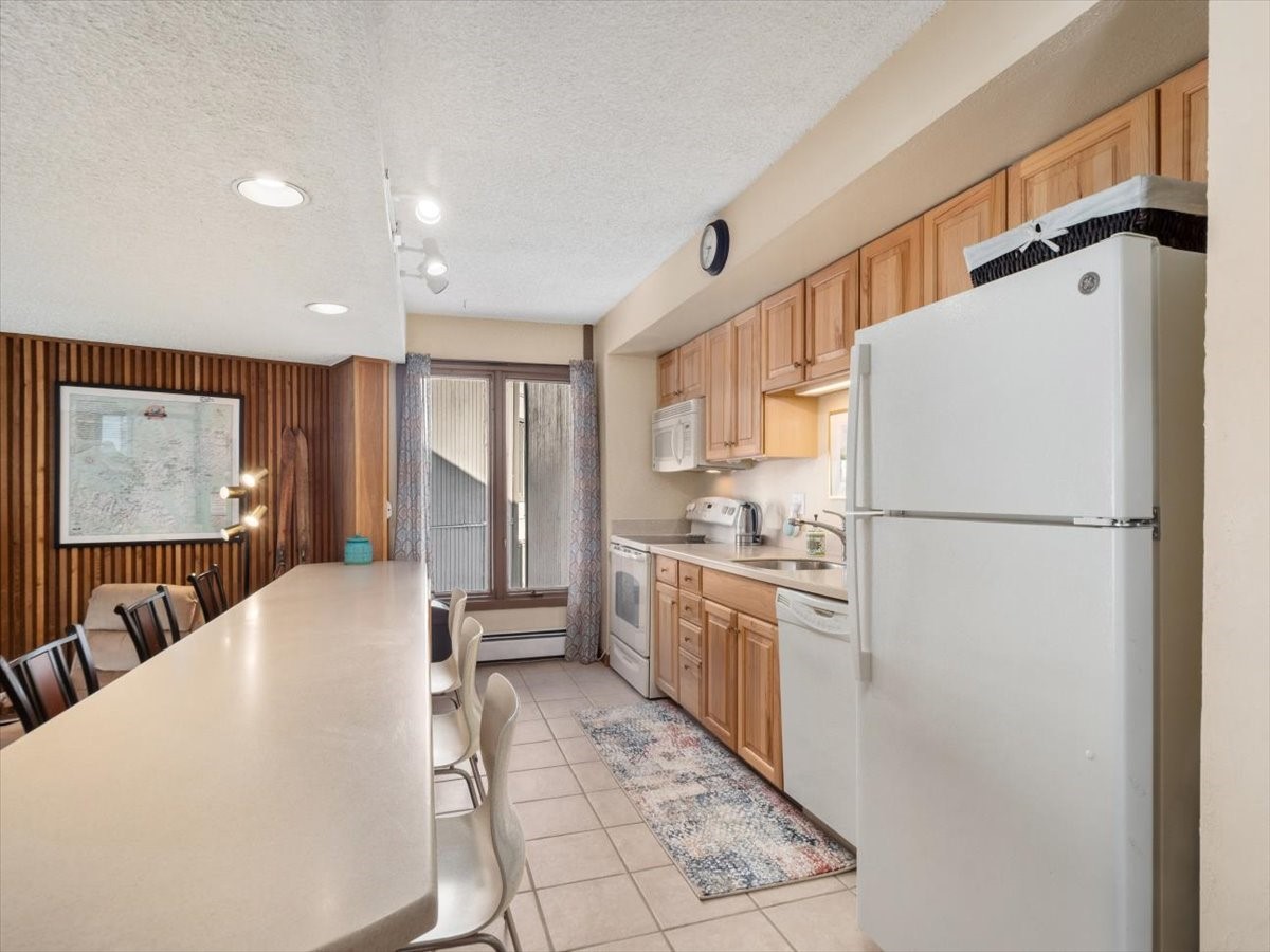 1161 Ski Hill Road, Unit 141 Breckenridge, CO 80424 - Photo 10 of 22 a kitchen with refrigerator a sink and white cabinets