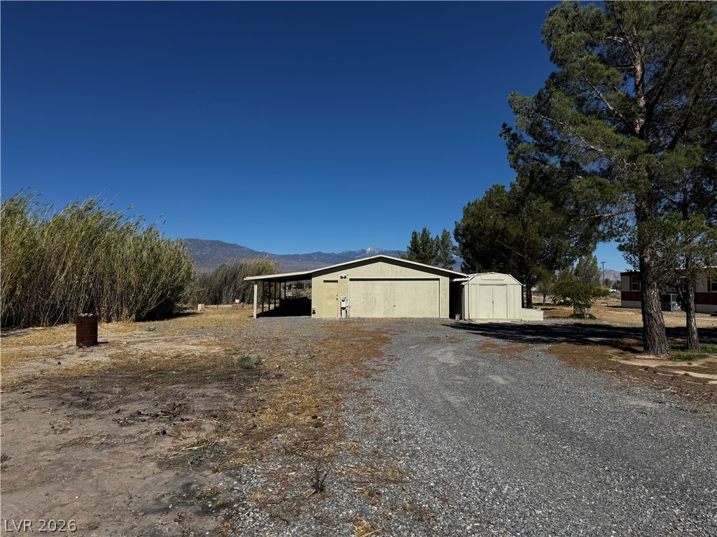 3090 Gally Road Pahrump, NV 89060 - Photo 2 of 20 A long gravel driveway leads to a spacious workshop with an attached covered carport.
