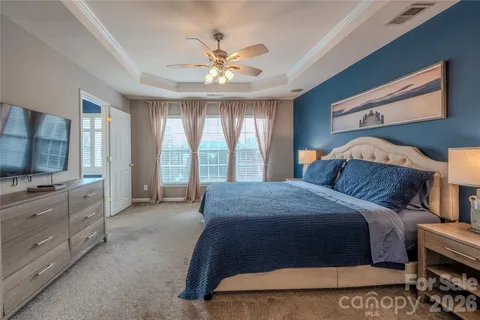 a bedroom with a large bed and a flat tv screen on dresser